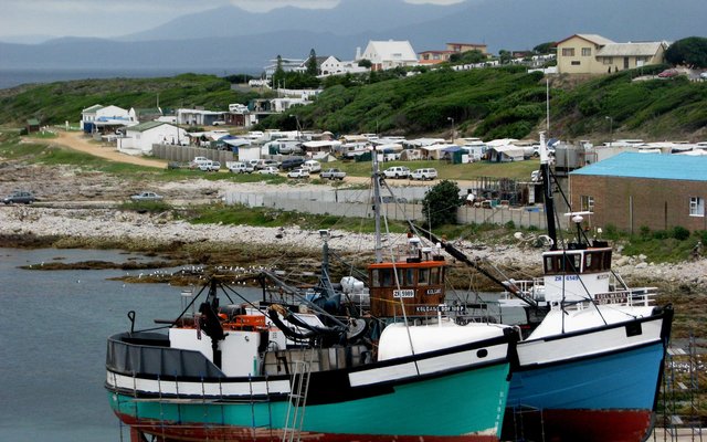 Desember kry Gansbaai se Vissermanne ‘n welverdiende blaaskans wanneer die bote herstel en opgeknap word, met ‘n vol Gansbaai Karavaanpark in die agtergrond  